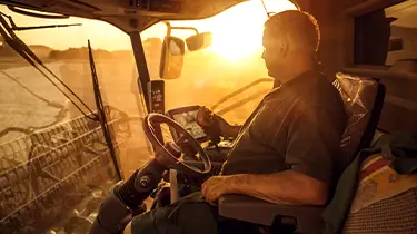 Farmer on combine harvest at sunset.